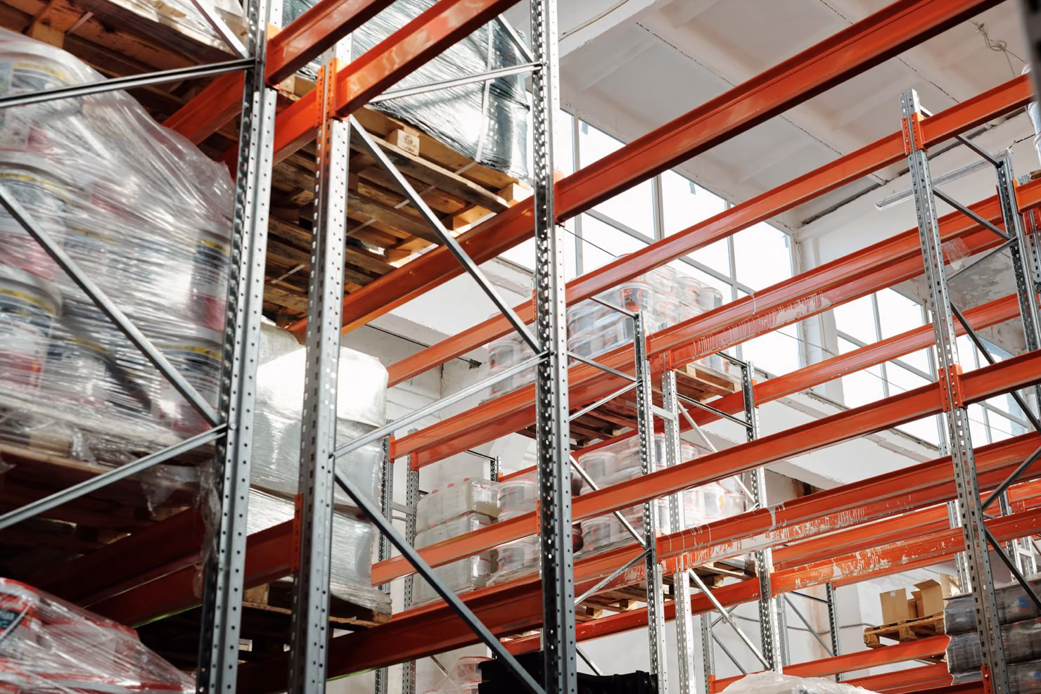 A view up pallet racking in a warehouse, with stacked pallets of goods on several levels.